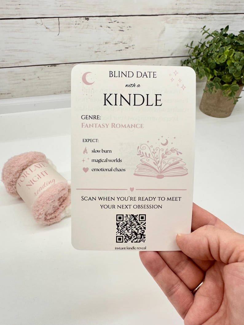 May include: A rectangular white card titled Blind Date with a Kindle, featuring the genre Fantasy Romance, a list of expectations including slow burn, magical worlds, and emotional chaos, a QR code, and the text Scan when you're ready to meet your next obsession.