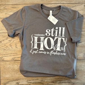 May include: Gray t-shirt with white text that reads "still HOT it just comes in flashes now".