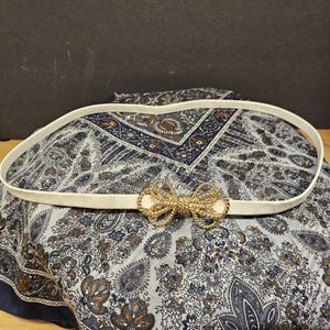 Vintage Mimi di N 1984 Skinny Belt, Gold Tone Interlocking textured Bow Buckle,  White Faux Leather Textured Belt