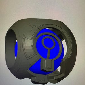 May include: A gray, futuristic-looking device with a blue orb at its center. The device has a circular design with geometric patterns and a central blue sphere. The overall aesthetic suggests a sci-fi or technological theme.