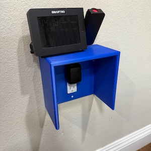 May include: A blue, wall-mounted shelf with a built-in electrical outlet. A black digital display with the text "SMARTRO" is mounted on the shelf, along with a black device and a black power adapter.