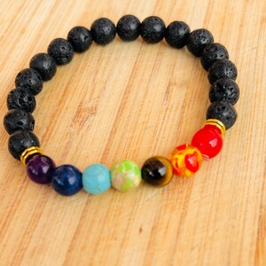 May include: A black lava rock bracelet with seven chakra beads. The beads are purple, blue, turquoise, green, brown, orange, and red.