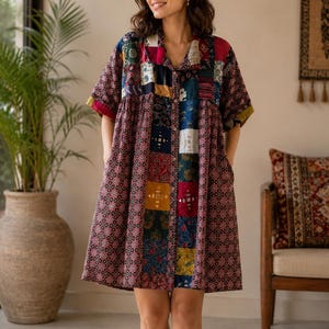 May include: A knee-length button-down dress featuring a patchwork design with various dark-toned floral and geometric patterns in shades of maroon, navy blue, yellow, and white. The dress has short sleeves, a collar, and side pockets.