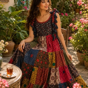 Puede incluir: Un vestido largo sin mangas con un diseño de patchwork que presenta varios patrones coloridos en tonos rojos, azules, amarillos y marrones. El vestido tiene un cuello redondo, tirantes con volantes que se atan arriba y una falda amplia.