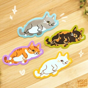 May include: Four colourful cat stickers with different coloured borders. The cats are in various poses, including sleeping and lounging. The stickers are perfect for adding a touch of whimsy to laptops, water bottles, or journals.