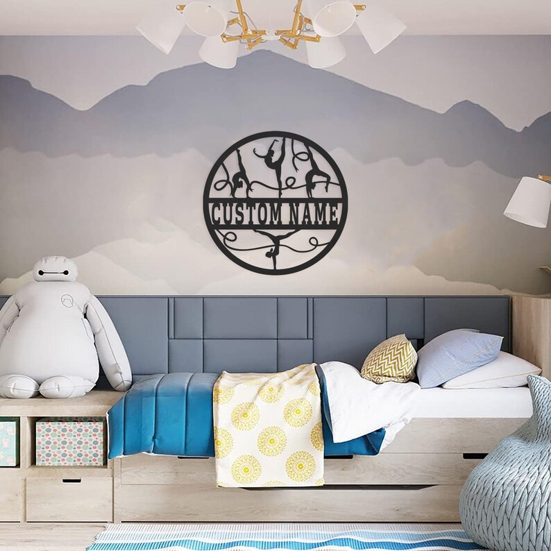 May include: Black metal wall decor featuring a circle with silhouettes of gymnasts performing on uneven bars. The circle has the text "CUSTOM NAME" in the center.