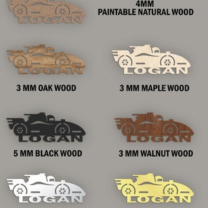 May include: A set of six personalized wooden and acrylic race car name plaques. The plaques are available in various wood types and colors, including natural wood, oak, maple, walnut, black wood, silver acrylic, and gold acrylic. The plaques are 3mm or 5mm thick and feature the name "LOGAN" in a racing font.