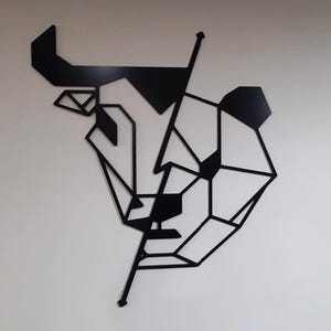 May include: Black and white geometric wall art featuring a bull and a bear head, with a line dividing the two animals.