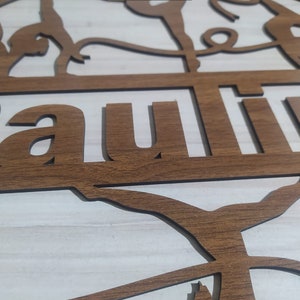May include: A wooden sign with the word "Lauren" cut out in the center. The sign is decorated with a silhouette of a gymnast performing on the uneven bars.