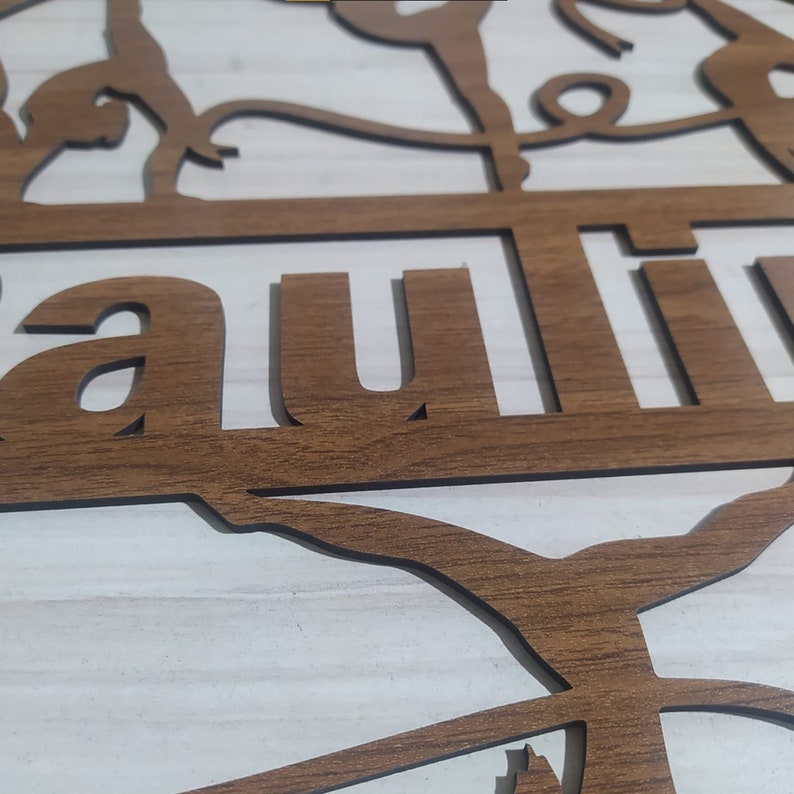 May include: A wooden sign with the word "Lauren" cut out in the center. The sign is decorated with a silhouette of a gymnast performing on the uneven bars.