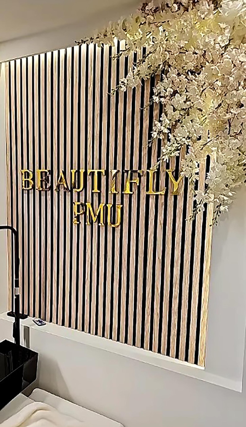 May include: A black and white striped wall with the words "BEAUTIFLY PMU" in gold letters.