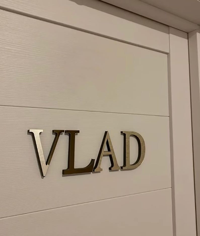 May include: A white door with the name "VLAD" spelled out in silver letters.
