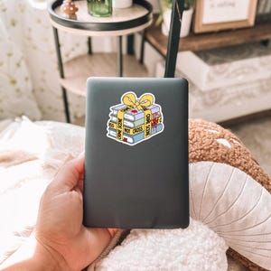 May include: A black laptop with a sticker of a stack of books wrapped in yellow crime scene tape. The tape reads "Crime Scene Do Not Cross".