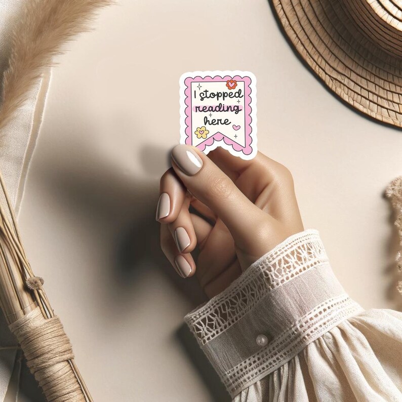 K&ouml;nnte beinhalten: Ein rosa-wei&szlig;er Aufkleber mit dem Text "Ich habe hier mit dem Lesen aufgeh&ouml;rt" in Bannerform mit Herzen und Sternen.