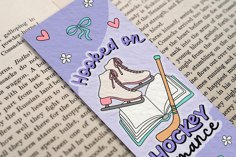 May include: A purple bookmark with a white book, ice skates, and a hockey stick. The bookmark has the text "Hooked on Hockey Romance" in purple letters.