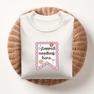 K&ouml;nnte beinhalten: Wei&szlig;es T-Shirt mit einem rosa Banner, auf dem "Ich habe hier mit dem Lesen aufgeh&ouml;rt" steht, mit einem Blumen- und Sternendesign.