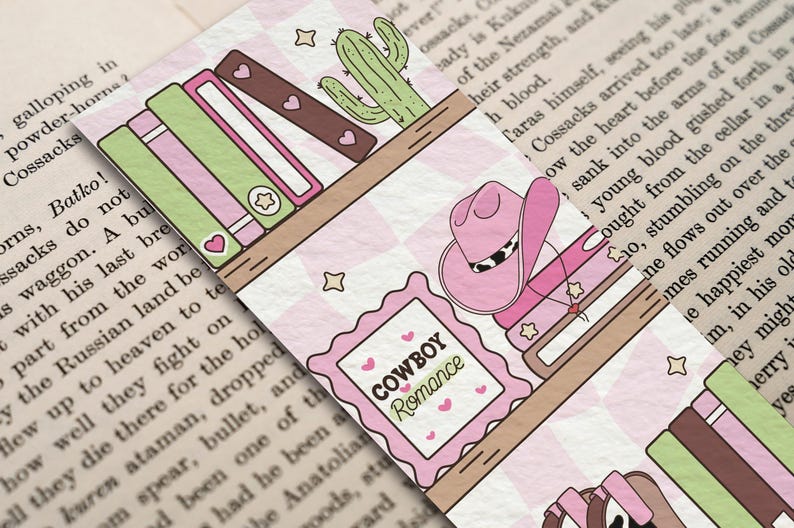 May include: A decorative bookmark featuring a pink cowboy hat, books, and a cactus on a shelf. The bookmark has the text "COWBOY Romance" in a pink frame. The background is a pink and white checkered pattern.