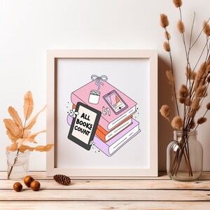 May include: A white framed print with a pink, orange, and purple stack of books. The top book has a white wireless earbud case and a pink phone with a screen that says "67". The print says "All Books Count" in black text.