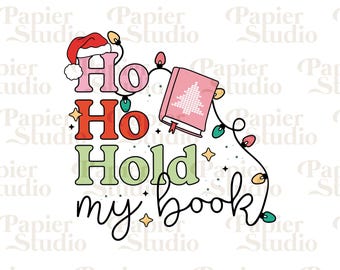 May include: A Christmas-themed design with the text "Ho Ho Hold my book" in red, green, and pink lettering. A pink book with a Christmas tree design is shown with a string of lights.