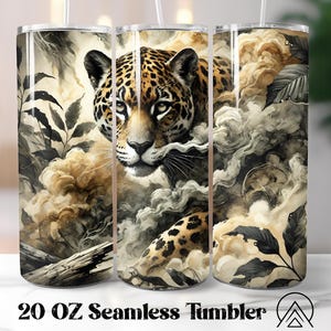 May include: A 20 oz seamless tumbler featuring a detailed illustration of a jaguar amidst swirling clouds and foliage. The jaguar's face is prominently displayed, showcasing its spotted coat and intense gaze. The design incorporates shades of brown, beige, and gray.