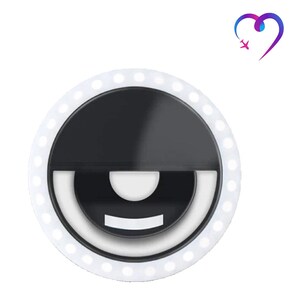 May include: A white ring light with a black center and a white circle around the edge. The ring light has a smiley face design with a white mouth and eyes.