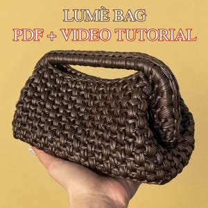 Può includere: Una borsa marrone intrecciata con manico. La borsa è tenuta in mano su uno sfondo giallo. Il testo "LUMÈ BAG PDF + VIDEO TUTORIAL" è visualizzato nella parte superiore dell'immagine.