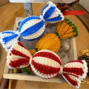 Può includere: Tre decorazioni di caramelle all'uncinetto a forma di caramelle avvolte. Una è a strisce blu e bianche, una è a strisce gialle e bianche e una è a strisce rosse e bianche.