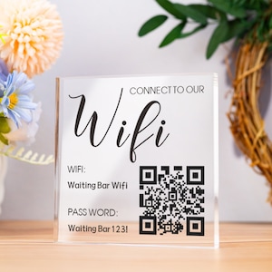Könnte beinhalten: Ein klares Acrylschild mit schwarzem Text und einem QR-Code. Das Schild sagt "Verbinden Sie sich mit unserem Wifi" und gibt den WLAN-Namen "Waiting Bar Wifi" und das Passwort "Waiting Bar 123!" an.