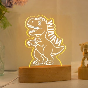 May include: A wooden night light shaped like a dinosaur with the name "William" written on it. The light is illuminated in a warm yellow color.