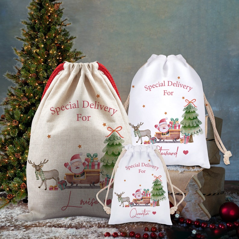 May include: Three Christmas-themed drawstring gift bags. The bags are beige and white, with red and beige drawstrings. Each bag features a Santa Claus design with a reindeer, Christmas tree, and the words "Special Delivery For" and a name.
