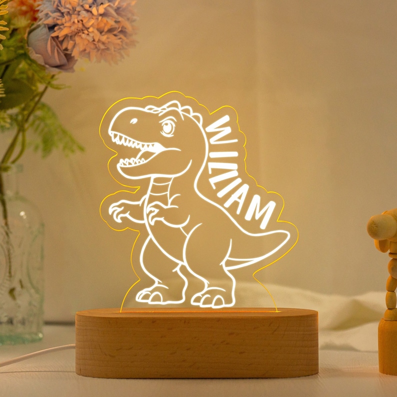 May include: A wooden night light shaped like a dinosaur with the name "William" written on it. The light is on and illuminating the dinosaur.