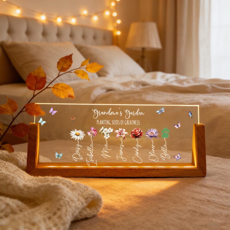 May include: A personalized LED light with a wooden base. The clear acrylic panel displays the text "Grandma's Garden" and "Planting Seeds of Greatness", along with names and floral illustrations. Butterflies are scattered across the panel.