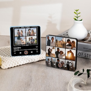 Puede incluir: Dos bloques de fotos personalizados que se asemejan a reproductores de m&uacute;sica. Uno tiene un marco azul claro, el otro negro. Cada uno muestra varias fotos, el texto "Love Story" y la fecha 21.01.2026. Los bloques est&aacute;n sobre una superficie de madera.