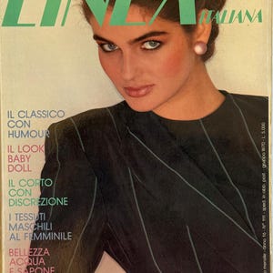 May include: Cover of "Linea Italiana" fashion magazine. The cover features a woman with dark hair and makeup, wearing a black pinstripe jacket. The magazine title is in large green letters. Text includes "The Italian Fashion Magazine" and "English Text".