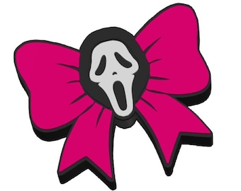 May include: A bright pink bow with a black trim, featuring a Scream mask at its centre. The mask is white with black detailing and a black outline. The bow is a vivid pink.