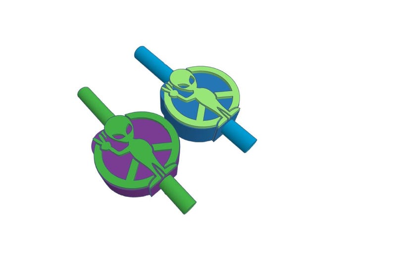 May include: Two green alien figures with peace signs on their chests are attached to colorful plastic straws. The straws are connected to each other.