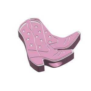 以下が含まれることがあります： 星の切り抜きが入ったピンクのカウボーイブーツのペア。ブーツはポインテッドトゥとスタックヒールです。ブーツは明るいピンク色で、濃いピンク色のトリムが付いています。