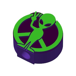 May include: A purple pencil sharpener with a green alien figure holding a peace sign inside a peace sign symbol.