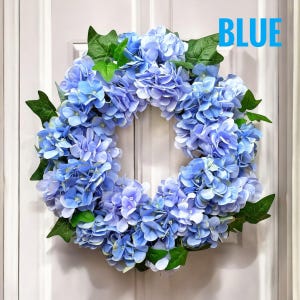 Può includere: Una ghirlanda di ortensie blu con foglie verdi. La ghirlanda è realizzata con fiori artificiali ed è perfetta per decorare una porta o un muro.