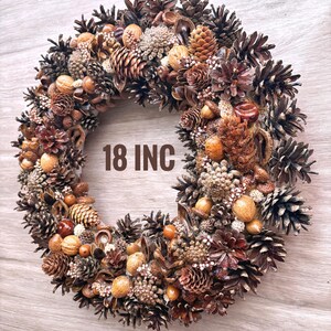 May include: A brown and gold 18 inch pine cone wreath with various natural elements, including acorns, nuts, and berries.