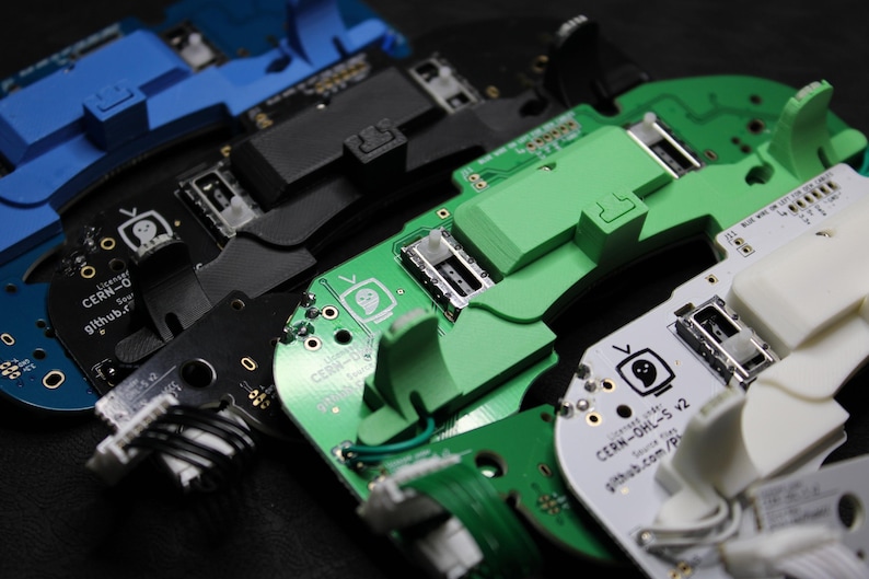 May include: Four circuit boards with different coloured plastic components. The boards are labelled "CERN-O", "CERN-D", and "CERN-OHL-S v2".