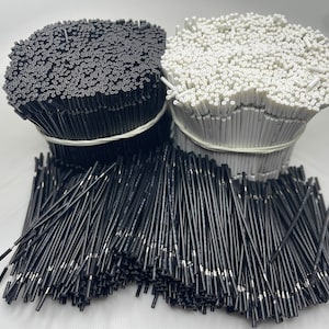 May include: A close-up of two bundles of black and white thin, flexible, plastic rods. The bundles are tied together with rubber bands.