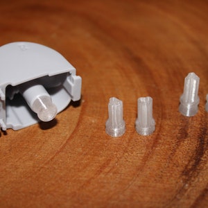 May include: A gray plastic part with a white plastic pin protruding from it. Three additional white plastic pins are laid out in a row.