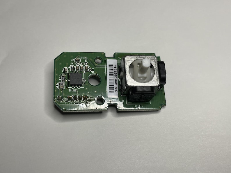 May include: A green circuit board with a small white joystick and the text "SN:2390F-68F-NS" printed on it.