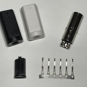 May include: A set of electrical connectors, including two black and white plastic housings, a silver metal connector, a black plastic connector, and a silver metal strip with five pins.