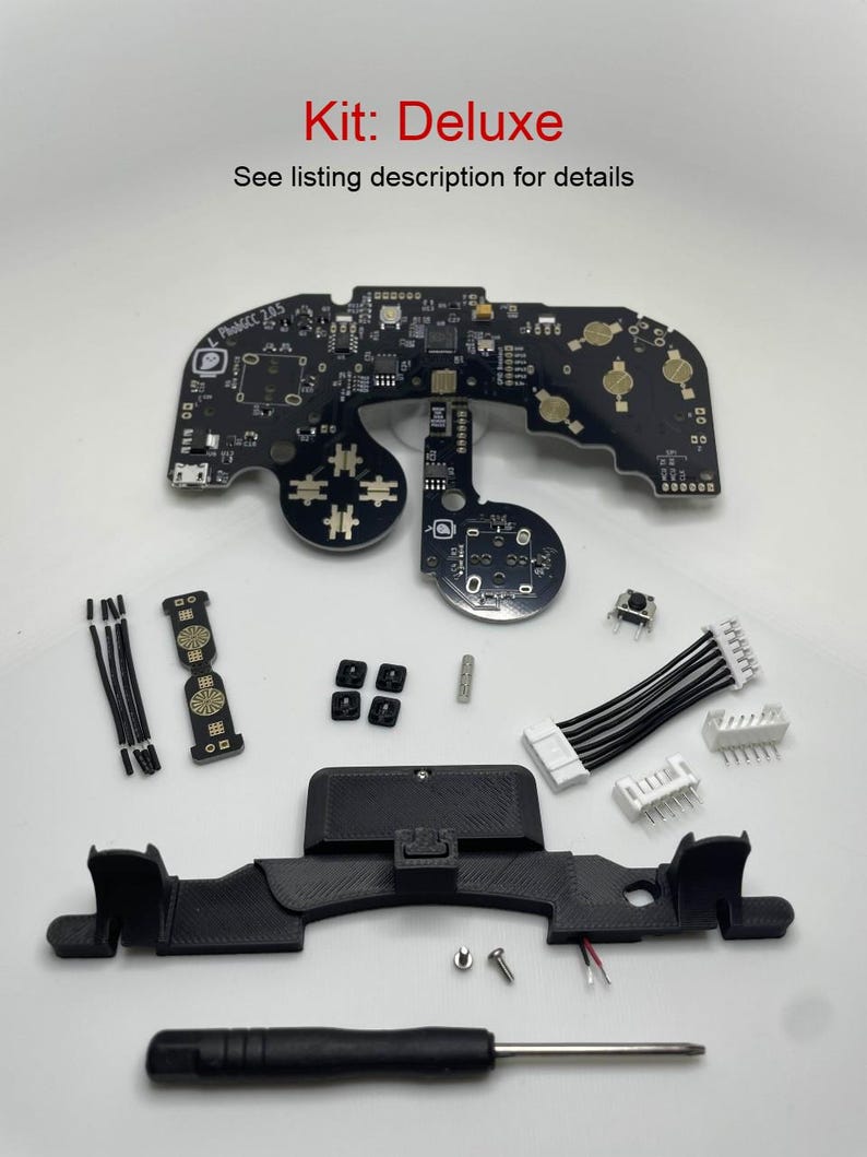 May include: A Deluxe kit for building a video game controller. The kit includes a circuit board, buttons, a screwdriver, and a 3D printed case. The kit is laid out on a white surface.