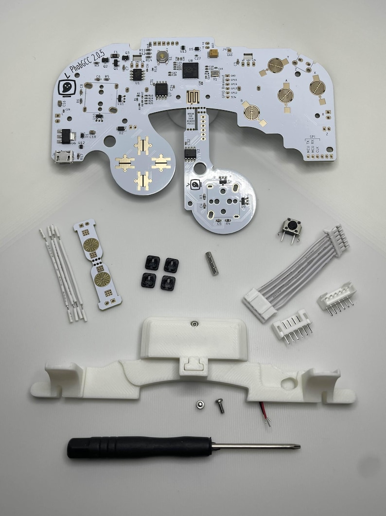 May include: A white circuit board with a white and gold button layout, a white screwdriver, and a white plastic case with a red wire. The circuit board has the text "L Phob6CC 2.0.5" printed on it.