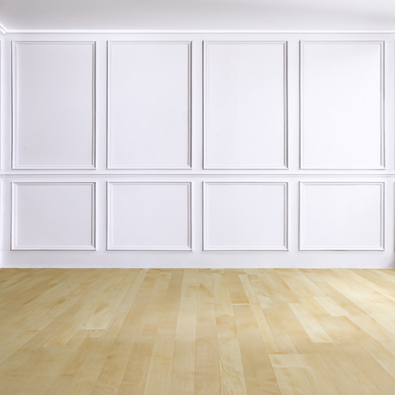 May include: A bright, empty room with white paneling on the walls and a light-colored wooden floor. The walls are divided into rectangular sections, creating a classic, clean aesthetic. The floorboards run horizontally, adding depth.