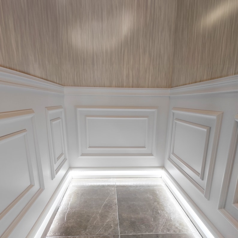 May include: A white room with white wainscoting and a beige ceiling. The floor is tiled in a light gray color. There is a strip of LED lights around the perimeter of the room.