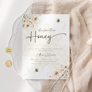 May include: A white bridal shower invitation with a watercolor background featuring a bee and flowers. The text reads "She found her Honey" and includes details for the event, such as the date, time, and location.